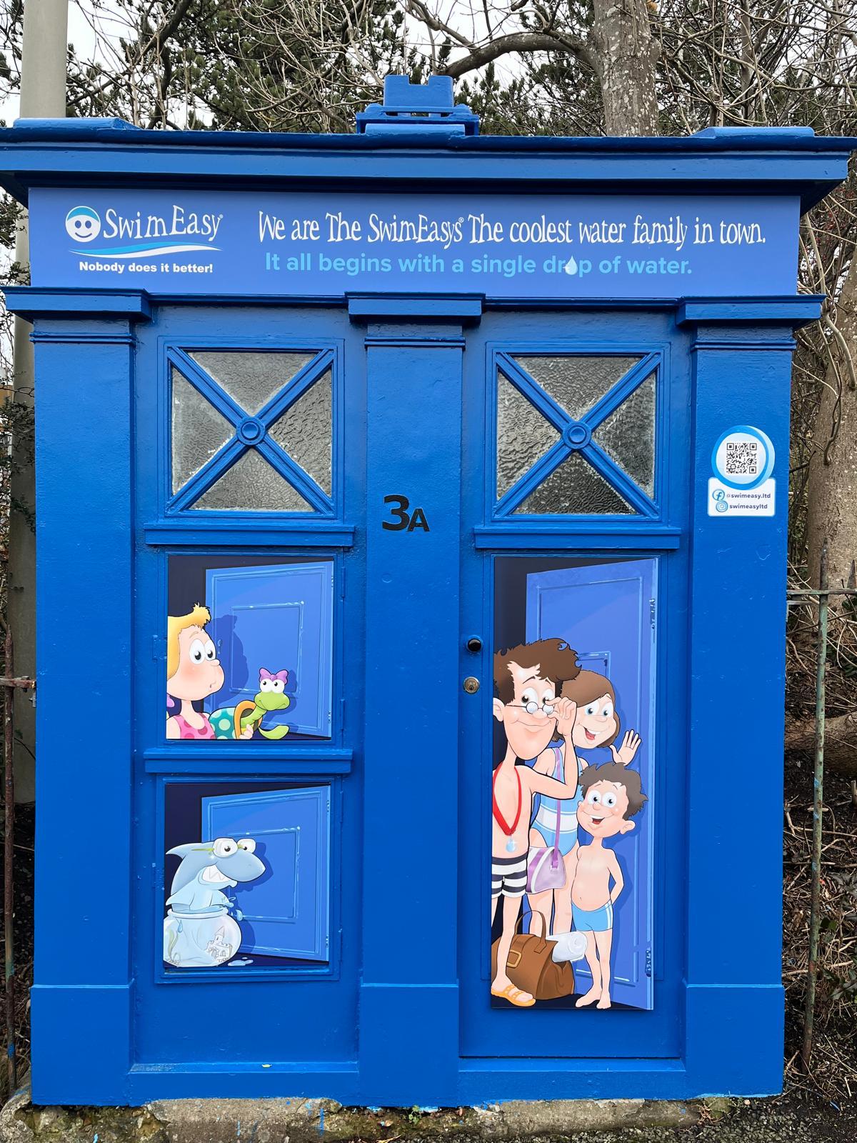 SwimEasy branded police box on Braid Hills Road Edinburgh, featuring illustrations of the SwimEasy family characters and missing Snapper the Shark teaser.